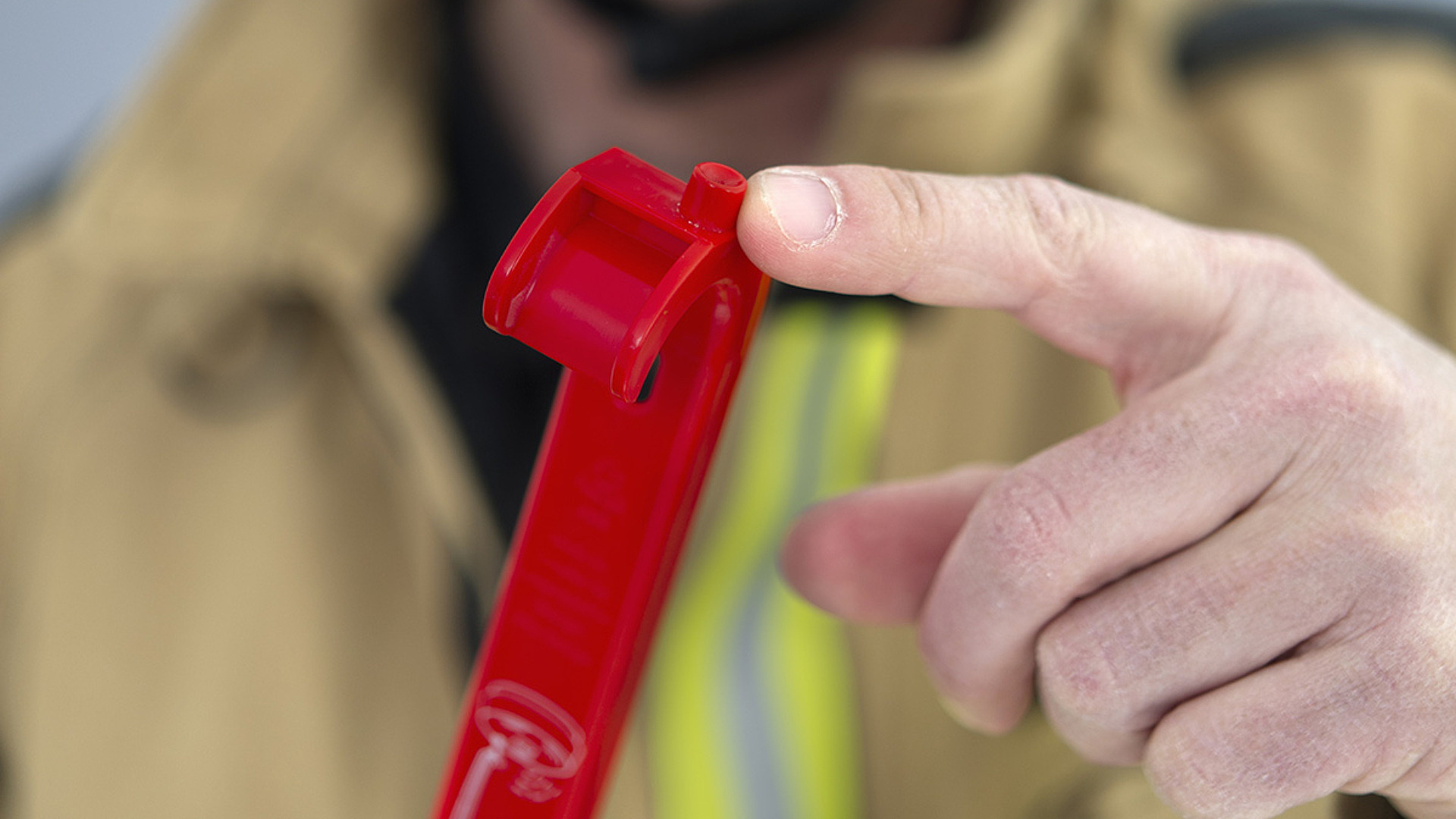 Närbild på brandman som pekar på ett rött skohorn för testning av brandvarnare