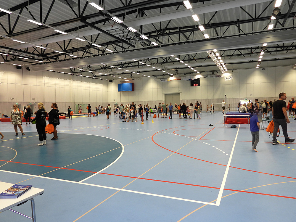 Många föräldrar och barn testar olika aktiviteter inne i en sporthall